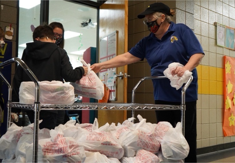 picture of worker giving a sack of food to students