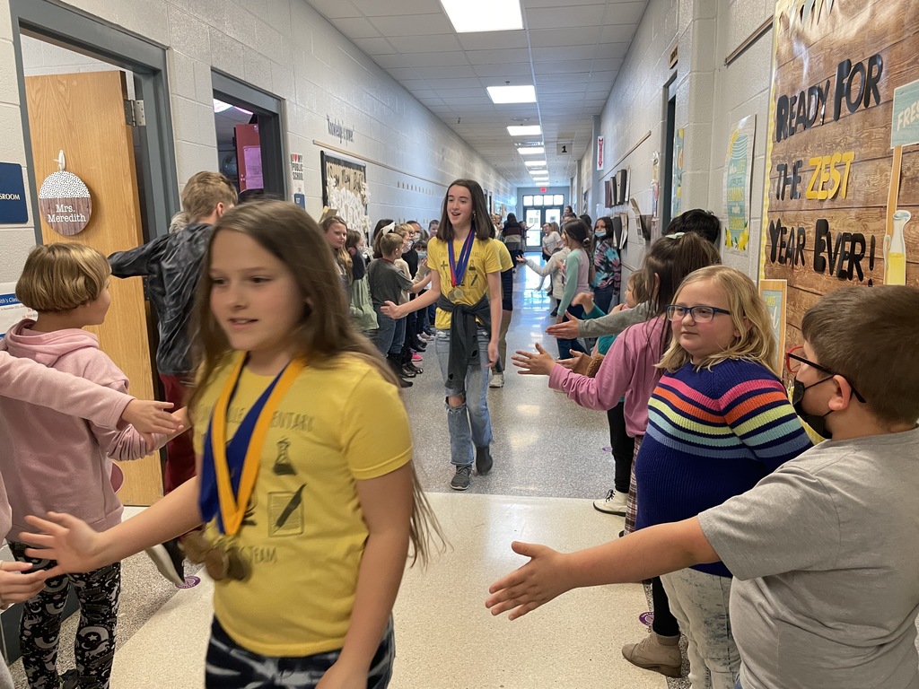 kids walking down a hallway high fiving other kids 