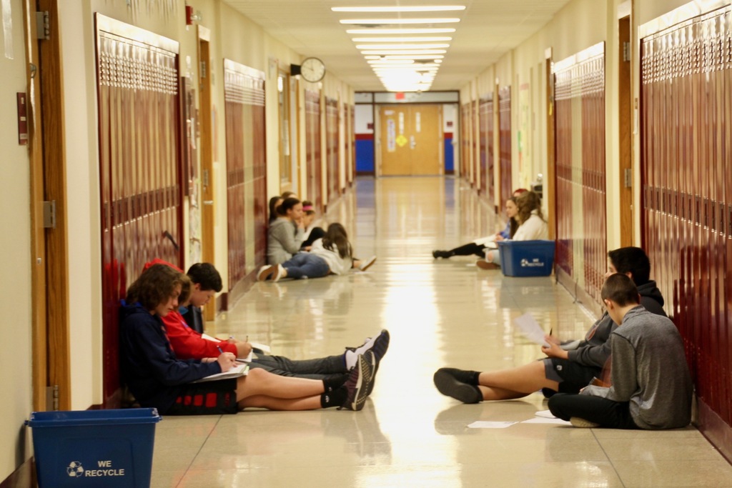 8th graders choose the hallway floor to work in small groups on a literacy project.