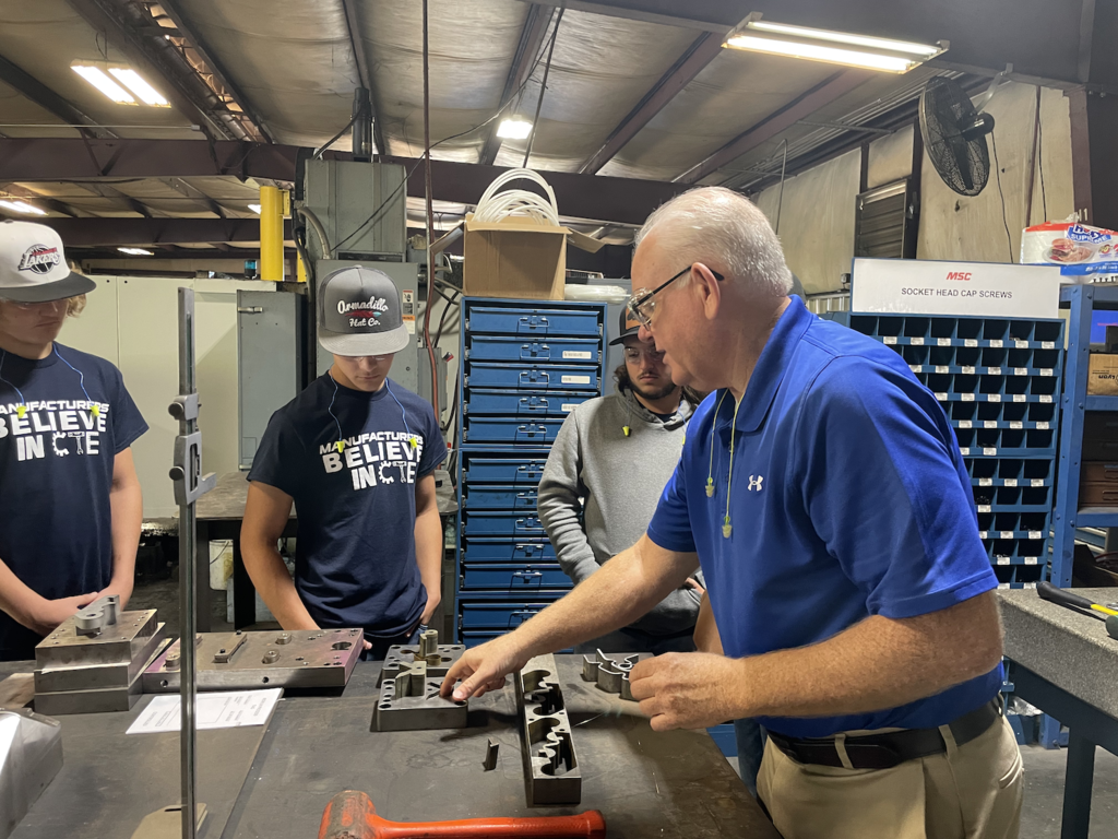 Man showing machining parts to male students