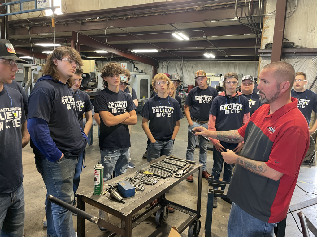 Man showing a welded part to students