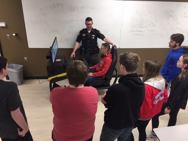 Officer Zempter working with RHS students in the distracted driving simulator
