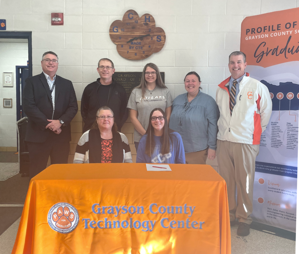 Men women and two students at a signing table