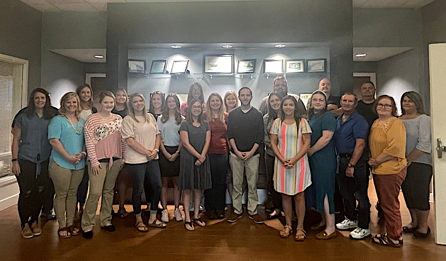 New GCS employees standing in row in front of a display case.