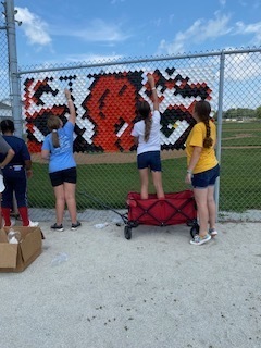 Students putting tiger on fence