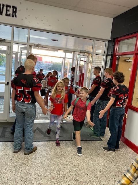 high school football boys with elementary students